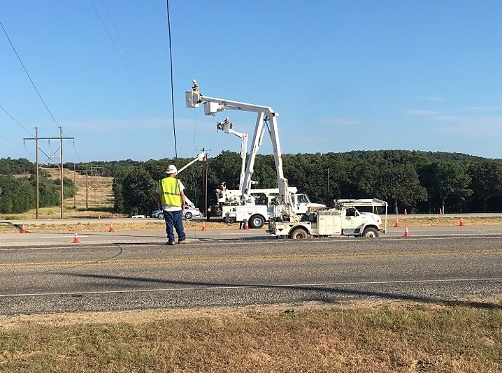 Scott Pole Line heavy equipment and trucks traveling across country to utility repairs. Shown here in bucket trucks, linemen are replacing power lines on new utility poles 